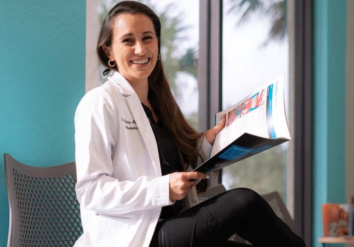 A smiling Vista Orthodontics clinician in a white coat reviewing treatment information