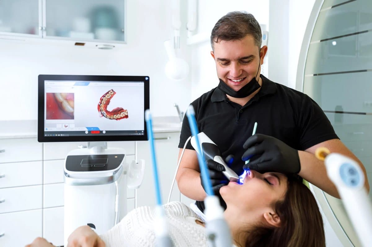 A Vista Orthodontics team member using a digital scanner, with a 3D model of teeth on the screen